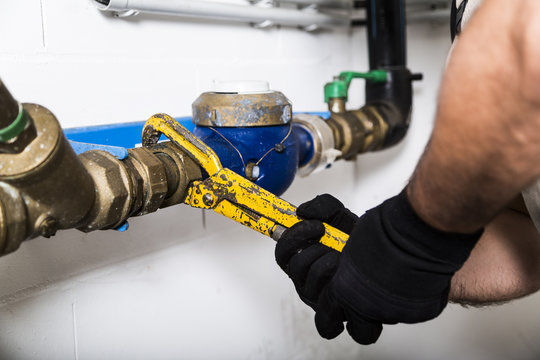 Plumber repairing metallic water pipes with manometer