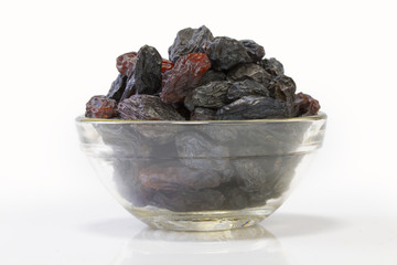 Black raisins in a glass bowl isolated on white background