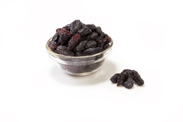Black raisins in a glass bowl isolated on white background