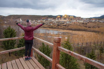 Fototapeta na wymiar Tourist woman standing and enjoy with beautiful landscape view of Songzanlin monastery golden temple land mark in Shangri-La city, China 