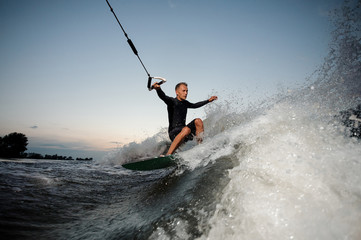 Active and young man riding on a wake board at the evening