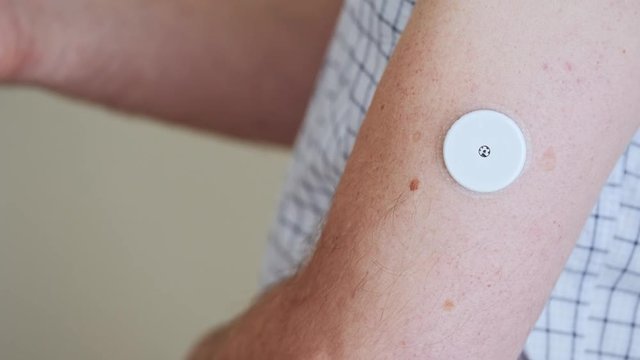 A man brings to the hand the reading device to the sensor for measuring glucose