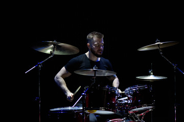 Fototapeta premium music, people, musical instruments and entertainment concept - male musician with drumsticks playing drums and cymbals at concert or studio