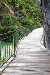 Long wooden bridge hang on cliff and above on river in Balagezong national park in Shangri-La city, China
