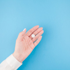 Female hand holding a white pill