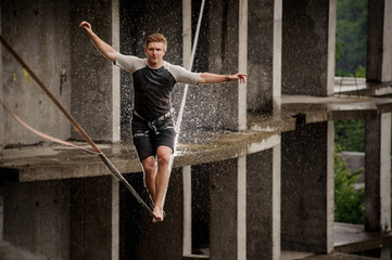 Strong and brave young man balancing on a slackline
