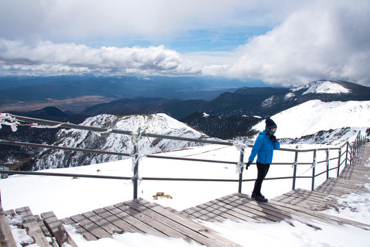 Tourist woman standing and enjoy view of beautiful snow mountains name "Shika snow mountains" on the top in Shangri-La, Yunan, China, acting and happy with cool weather on peak.