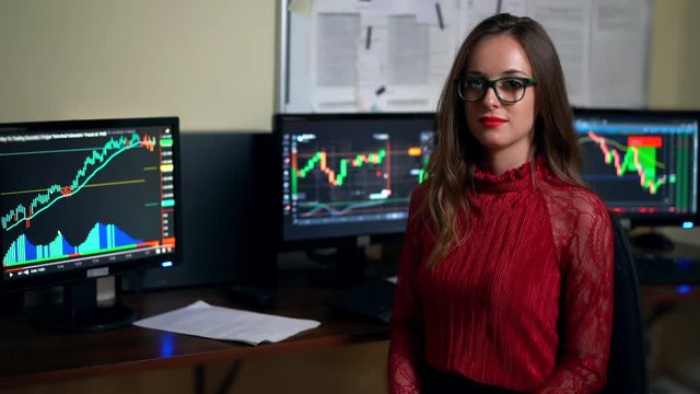 Financial advisor on the background of monitors full of trade diagrams.Company assistent working in office with trading profits. Shot in 4K (UHD).