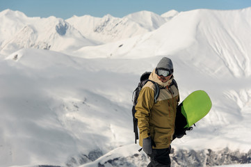 Fototapeta na wymiar guy in ski equipment is holding a green snowboard