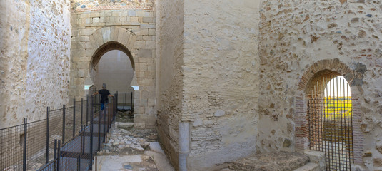 Visitor walking towards shoehorse arch of Alcazaba of Badajoz, Spain