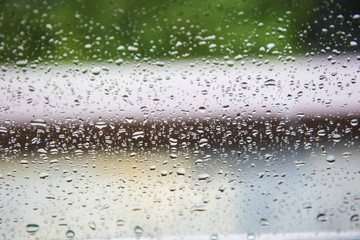 Rain drops by the office glass. There are houses and trees outside the window. Like a fog. 