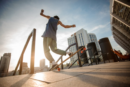 Young active man jumping on skateboard against the city buildings