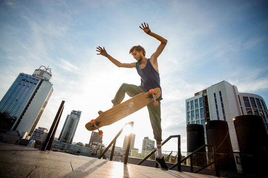 Young skateboarder jumping on board against city buildings