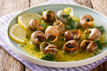 Cooked French snails, escalgot with butter, herbs, lemon and garlic close-up on a plate. horizontal