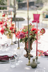 Rustic banquet, candels, glasses, red and pink flowers. Elegance and light is around