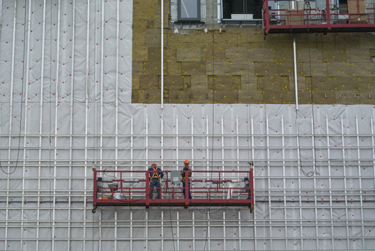 Construction of a hotel. Workers on suspended scaffolding 