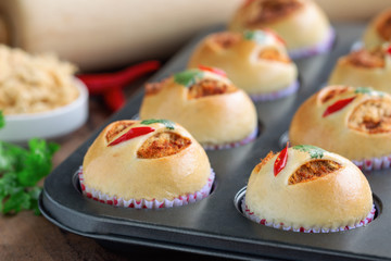 Homemade cup of soft and sticky bun with dried shredded pork or pork floss and shrimp roasted chili paste in muffin tray on wood table. Thai style delicious bread with sweet and spicy taste for snack.