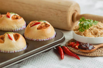 Homemade cup of soft and sticky bun with dried shredded pork or pork floss and shrimp roasted chili paste in muffin tray on wood table. Thai style delicious bread with sweet and spicy taste for snack.