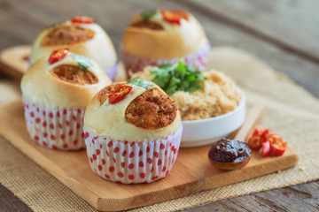 Homemade cup of soft and sticky bun with dried shredded pork or pork floss and shrimp roasted chili paste on wood table with ingredients. Thai style delicious bread with sweet and spicy taste.