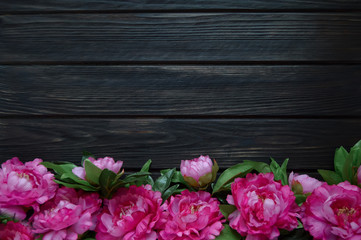 a dark wooden background with peony flowers. space for text