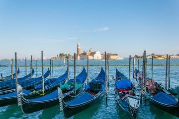 Fototapeta na wymiar Pack of gondolas docked in Saint Mark's square Venice, in the background it can be seen a church with a bell tower 