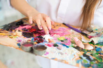 Fototapeta na wymiar Сute girl artist paints on canvas painting on the easel. Model in the studio