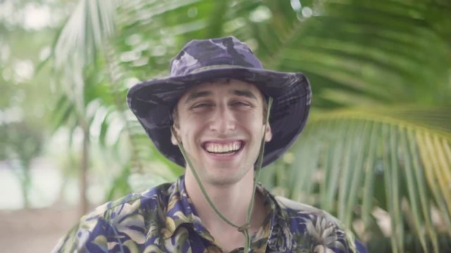 Young explorer gives thumbs up to camera while exploring tropical jungle. Big smile on his face