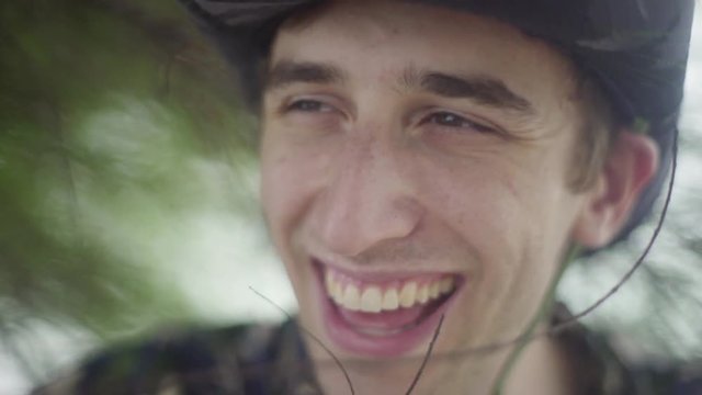 Attractive white young man smiling and lauhing into the distance. Wearing explorer hat in the jungle