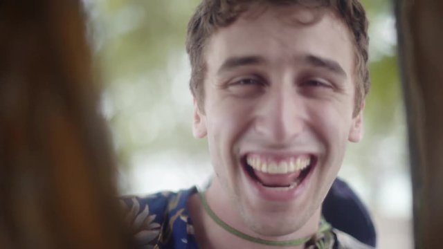 Happy young white man playing peek-a-boo into the camera. Smiling and laughing Enthusiastically.