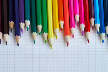 Colored pencils on a checked notebook. Close-up, top view