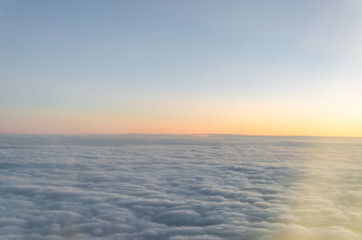 Photograph of a landscape from the sky full of clouds in full sunrise with some orange tones.