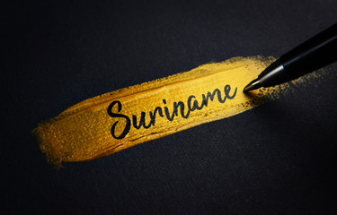 Suriname Handwriting Text on Golden Paint Brush Stroke