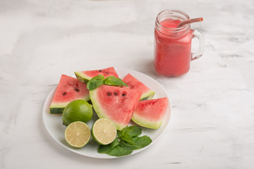 Smoothies with watermelon and slices from a watermelon in a plate with lime and mint. The summer mood
