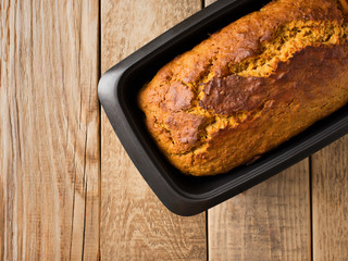 Homemade loaf cake on wooden background.