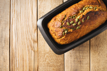 Homemade pumpkin cake with seeds on wooden background.