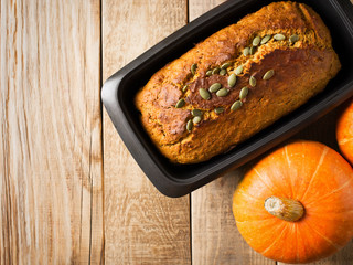 Homemade pumpkin cake with seeds on wooden background.