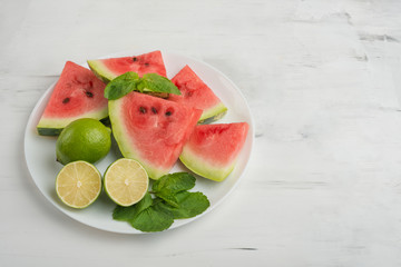 pieces from a watermelon in a plate with lime and mint. The summer mood