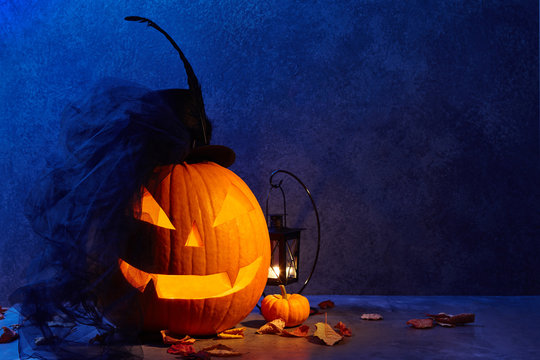 Halloween pumpkin head jack lantern with black bride hat in dark barn, holiday concept