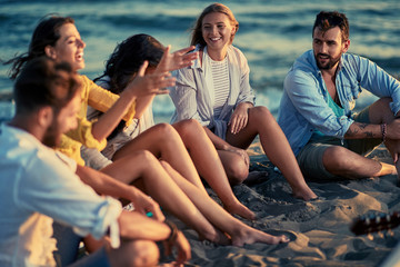 Summer, holidays, vacation, music, happy people concept - group of friends with guitar having fun on the beach.
