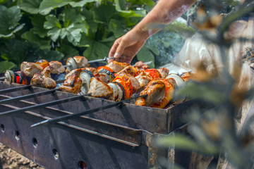 the man sets the meat on the skewer, prepares on the grill delicious barbecue