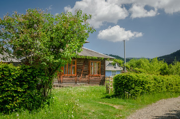 View of rural area at mountains taken at sunny spring day. Old wooden house  surrounded with trees and sky. Concept natural life in clear environment. Peaceful and calm feel of life without any hurry.