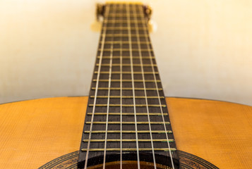 Obraz premium Fretboard and neck of a classical or spanish guitar with blur effect in background and clear natural light. Close up view of a musical instrument.
