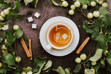 Cozy autumn flatlay with cup of warm tea, apple tree branches and cinnamon sticks on wooden table