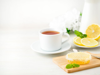 White Cup of tea, honey, honeycomb, lemon on white background. Folk method of treating colds. Side view, selective focus