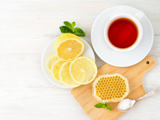 White Cup of tea, honey, honeycomb, lemon on white background. Folk method of treating colds, top view