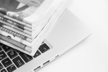 Newspapers and laptop. Pile of daily papers with news on the computer. Pages with headlines,...