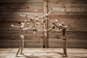 wooden puppets with atom construction on wood table in wood scene
