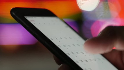 User looking at calendar dates on a smartphone - schedule for summer holiday vacation, business meatings, appointments, new initiatives concept