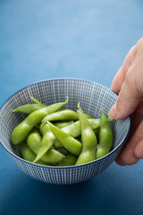 Frau isst Portion grüne, japanische Edamame Sojabohnen in Porzellan Schale