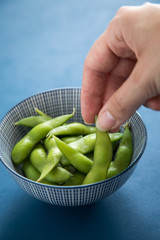 Frau isst Portion grüne, japanische Edamame Sojabohnen in Porzellan Schale